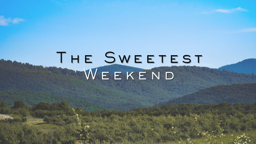 A panoramic view of an apple orchard stretching across the foreground, with lush Blue Ridge Mountains beneath a bright blue sky. Text over the image reads “The Sweetest Weekend.”